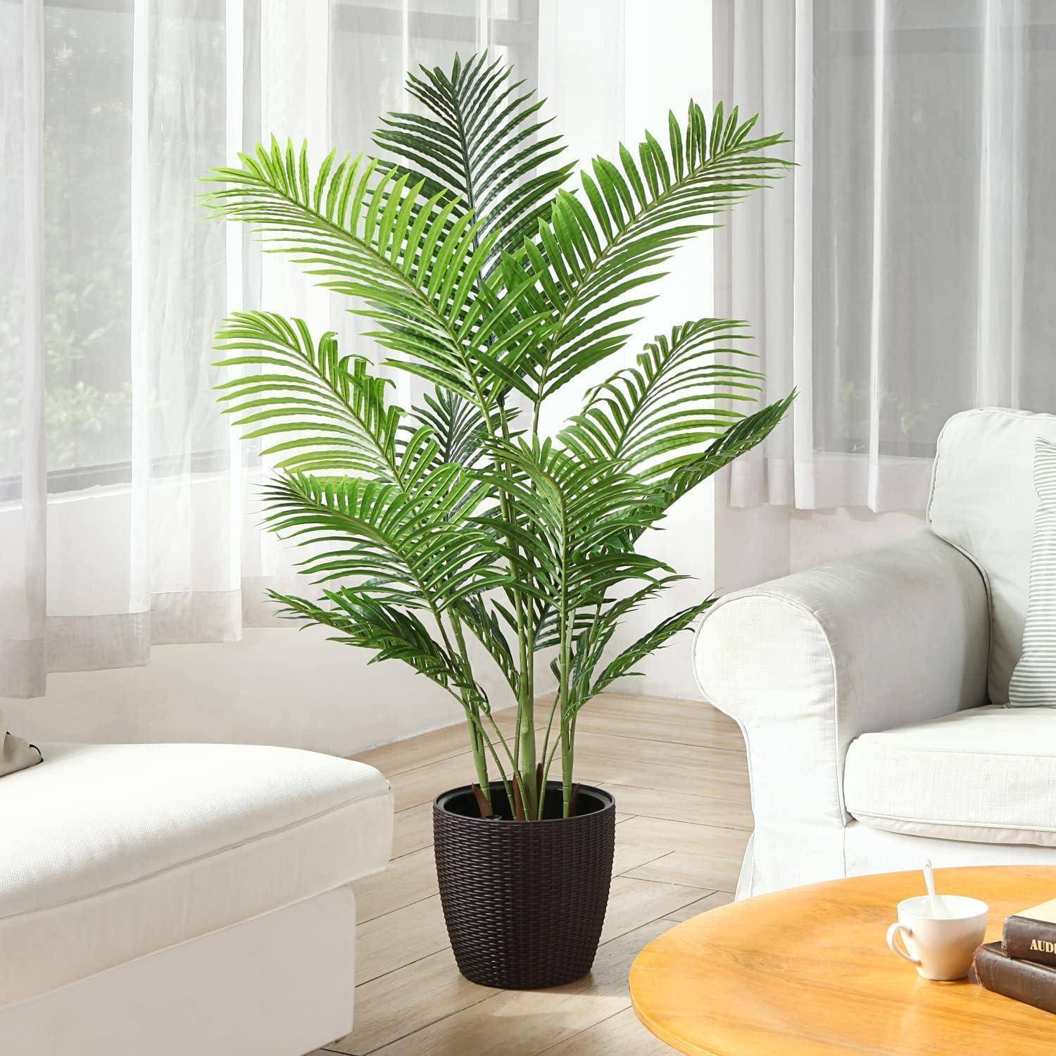 Eine Palme im Topf steht neben einem großen Fenster, flankiert von einem weißen Sofa und einem runden Holztisch, in einer sonnendurchfluteten Ecke des Wohnzimmers.