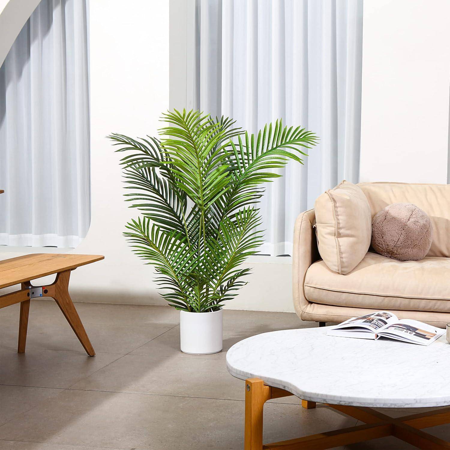 Ein modernes Wohnzimmer zeigt eine grüne Topfpflanze, ein beiges Sofa mit Kissen, einen Holzkaffeetisch und bodenlange Vorhänge.