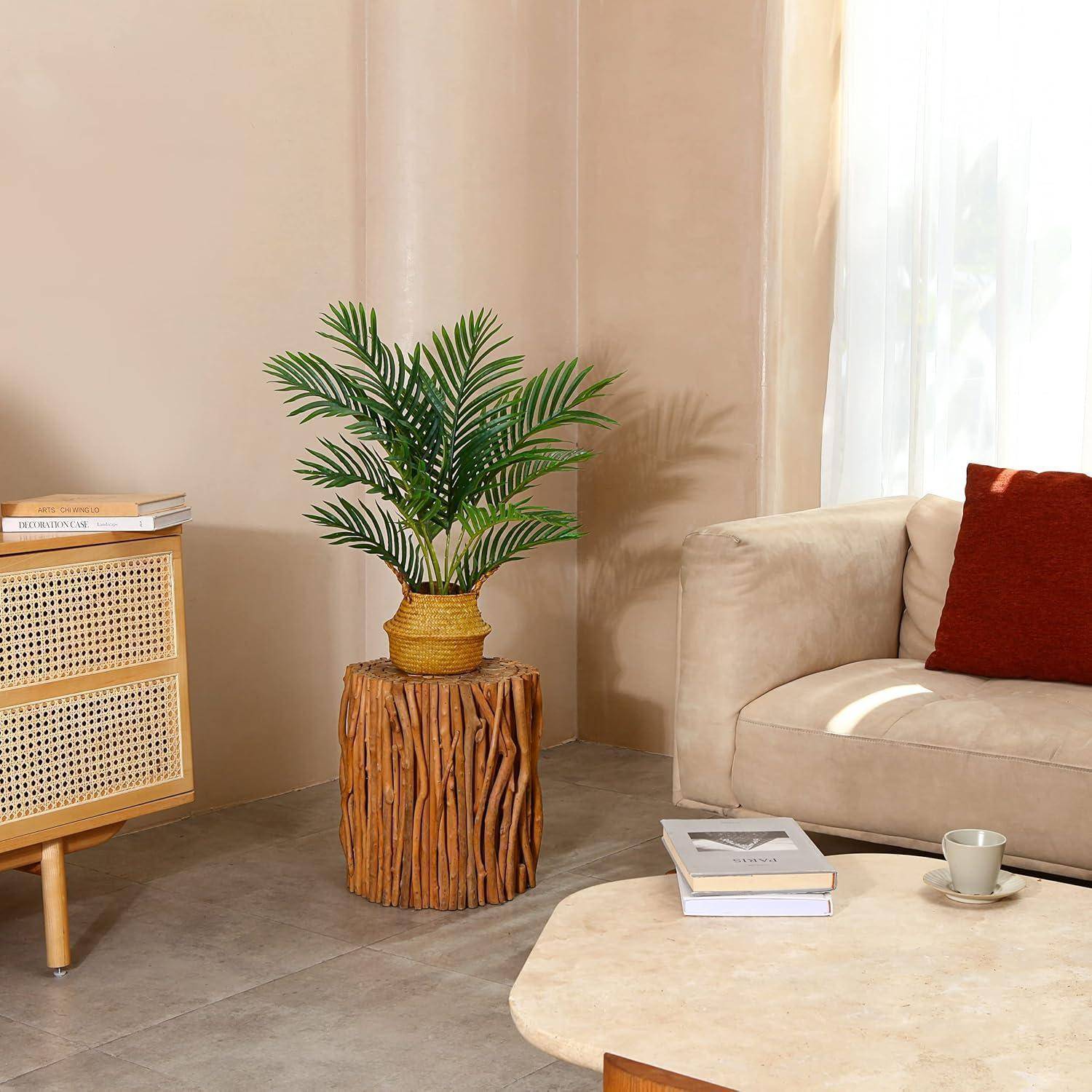 Eine gemütliche Ecke eines Wohnzimmers mit einem beigen Sofa und einem roten Kissen, einem Holzbeistelltisch mit einer Pflanze und weichem, natürlichem Licht.