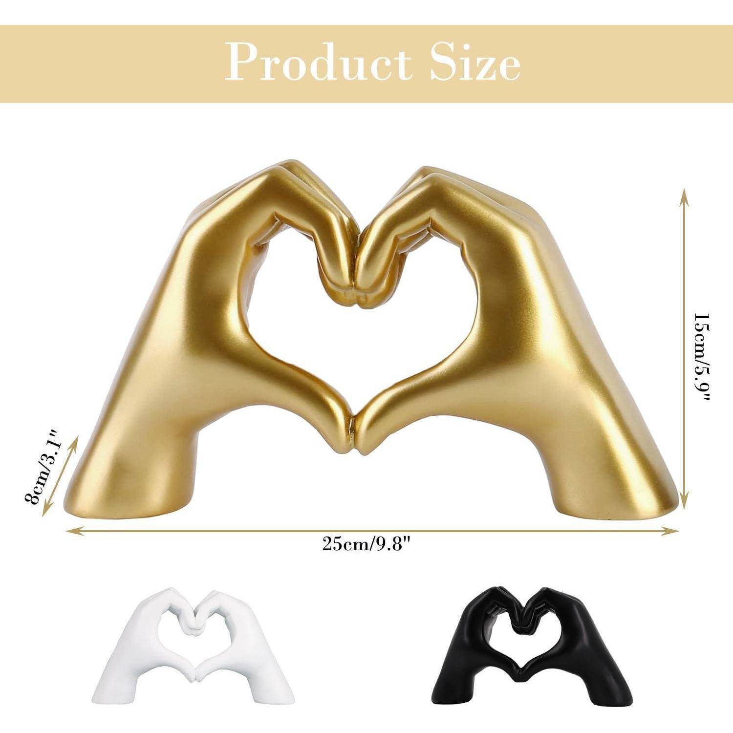 Goldene Handskulptur in Herzform, mit Abmessungen: 15 cm Höhe, 25 cm Breite. Zwei kleinere Varianten in Weiß und Schwarz gezeigt.