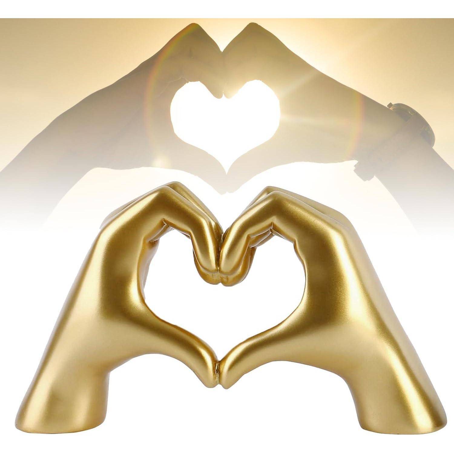 Zwei Hände bilden Herz-Formen; eine im Hintergrund mit durchscheinendem Licht, und eine goldene Skulptur im Vordergrund.