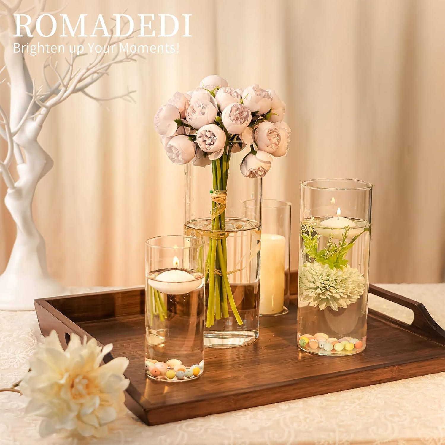 Ein Holztablett mit Kerzen, Blumenvasen und dekorativen Steinen. Eine Vase enthält rosa Rosen und verstärkt eine warme und elegante Atmosphäre.