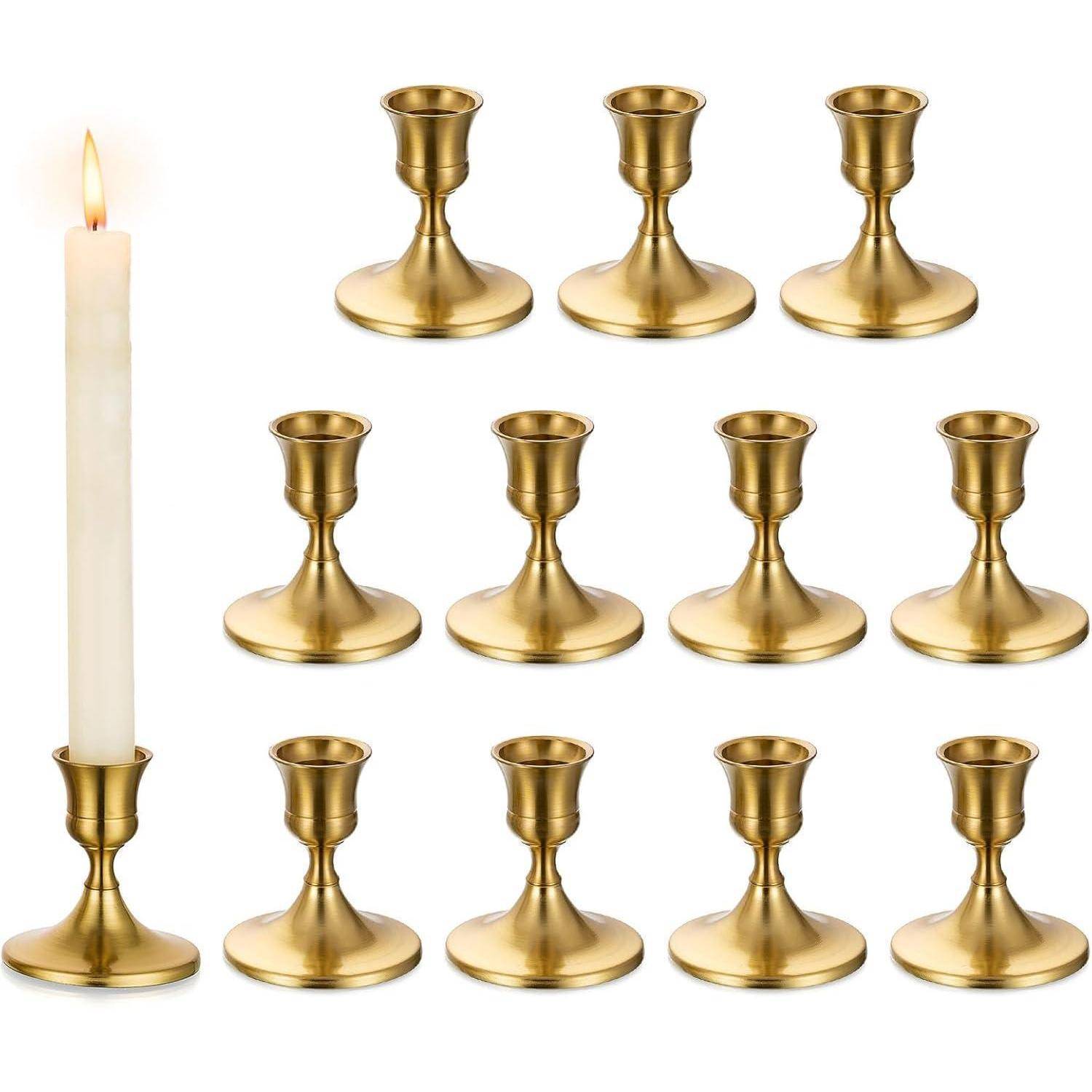 Eine Gruppe von 11 Messingkerzenhaltern und einer brennenden weißen Kerze auf der linken Seite, die das Design der Kerzenhalter präsentiert.