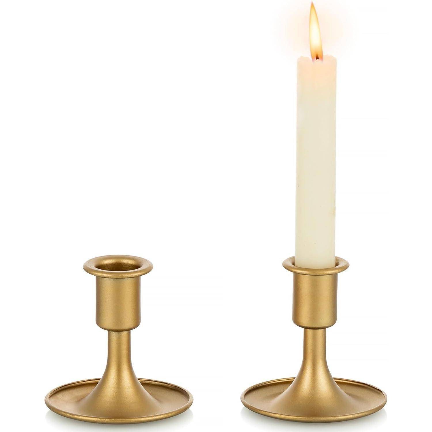 Goldene Kerzenhalter, einer mit einer brennenden weißen Kerze und einer leer, auf weißem Hintergrund.