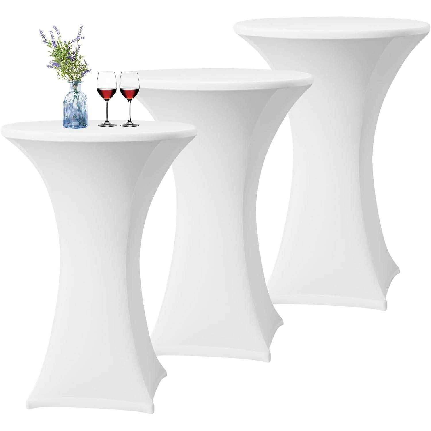 Drei hohe, runde weiße Tische mit passenden Bezügen; ein Tisch hat eine Vase mit lila Blumen und zwei Gläsern Rotwein darauf.