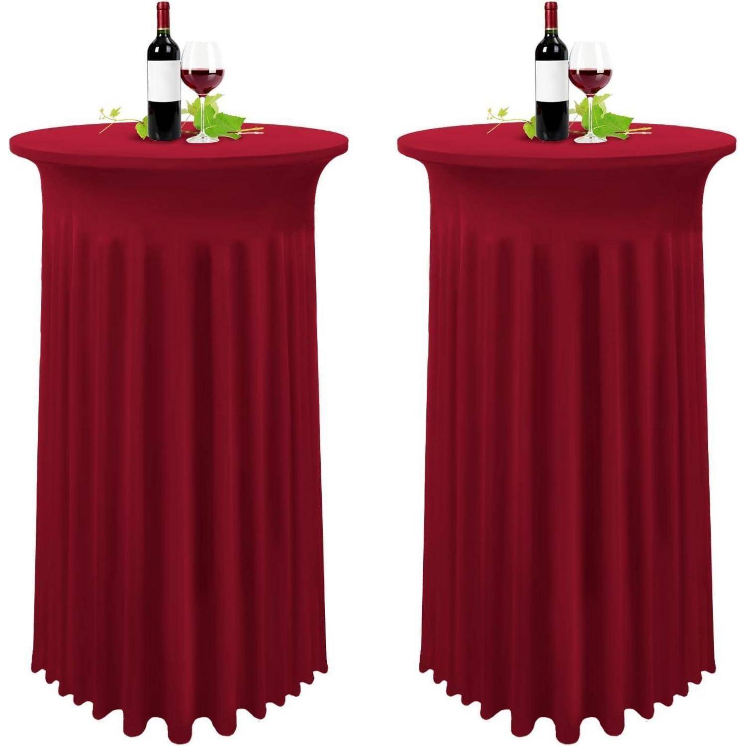 Zwei rot drapierte Cocktailtische mit Weinflaschen, Gläsern und Weinreben-Dekoration obenauf.