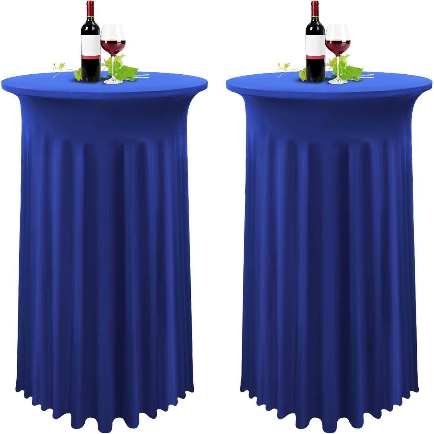 Zwei hohe runde Tische mit blauen Tischdecken, die jeweils eine Weinflasche, ein Glas und grüne Blätter tragen.