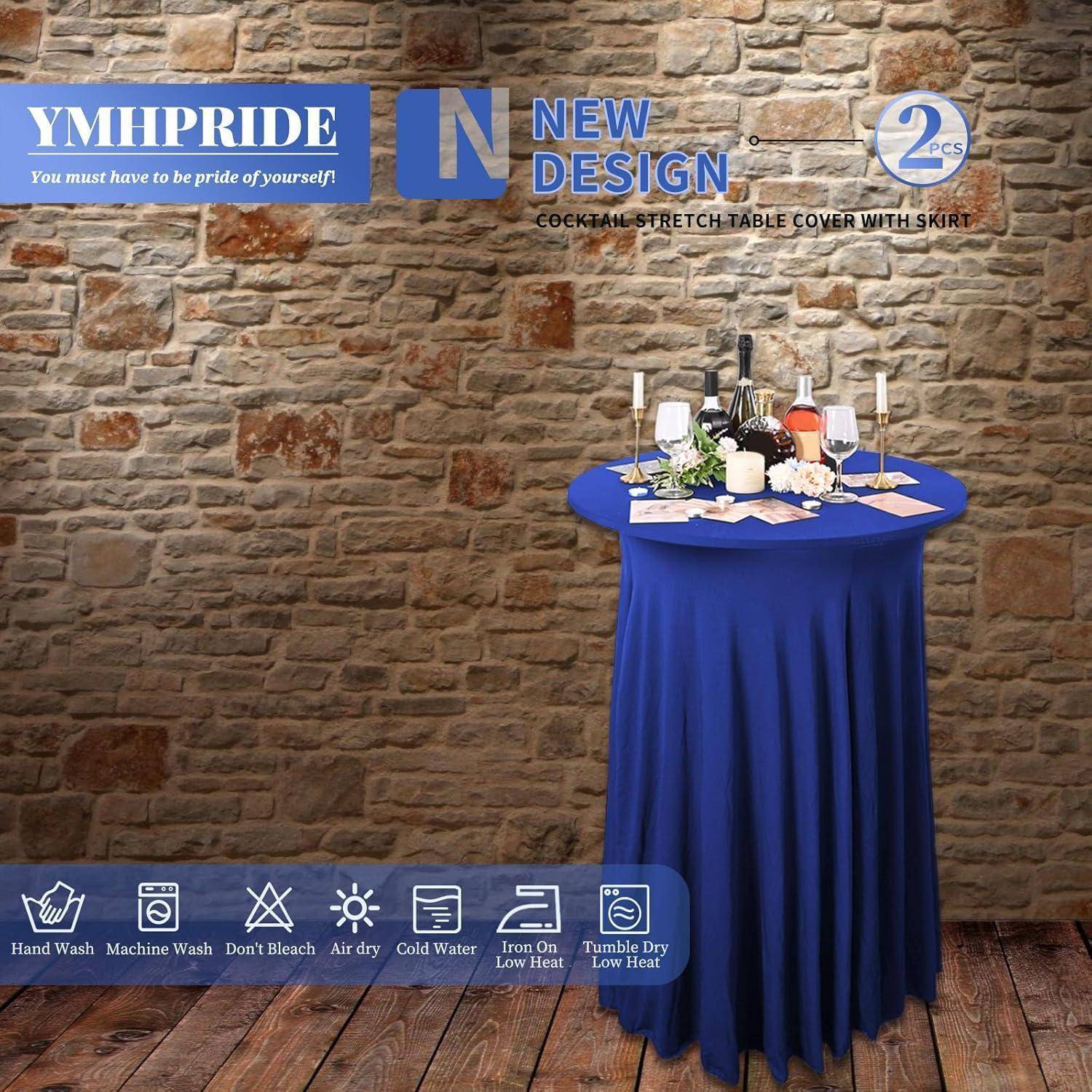 Ein rundes Cocktailtisch mit einer blauen Stretchhülle und Behang steht vor einer Ziegelwand. Der Tisch ist elegant mit Kerzen, Weingläsern und Flaschen dekoriert.