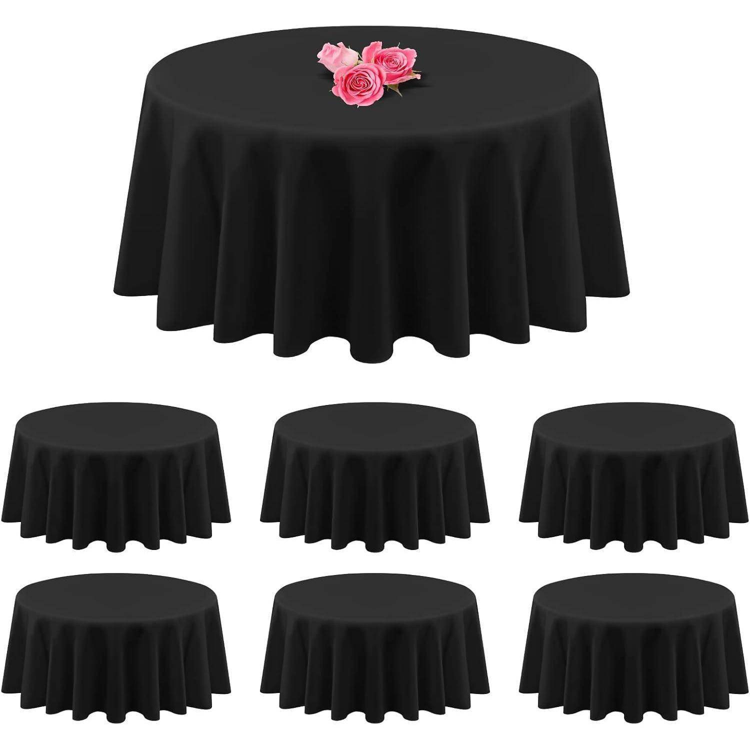 Runde schwarze Tischdecken in verschiedenen Größen, die jeweils über einen Tisch drapiert sind. Der Haupttisch ist oben mit einer kleinen Anordnung von pinken Rosen versehen.