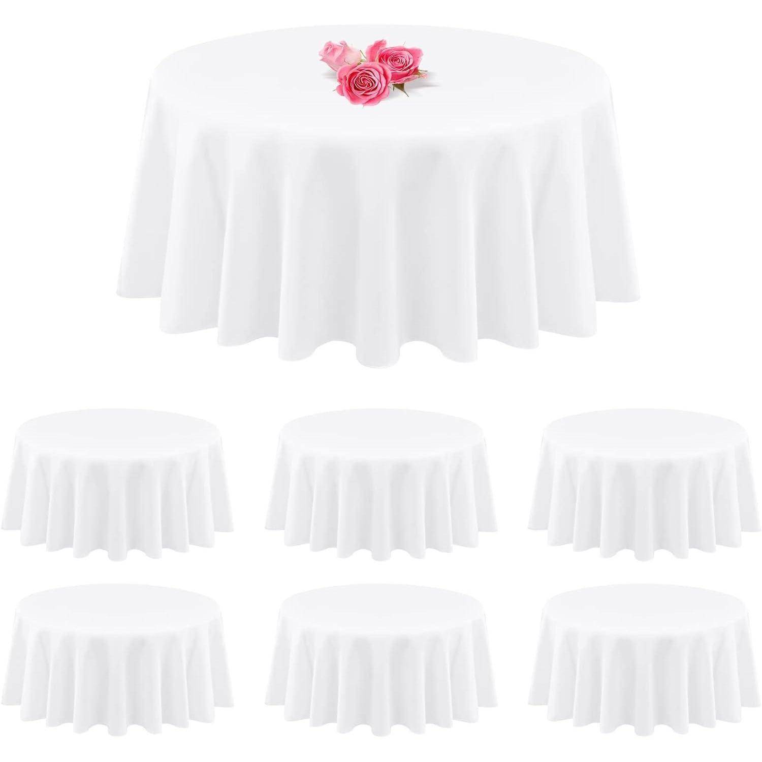 Sieben runde Tische, mit weißen Tischdecken behangen, wobei ein Tisch drei pinke Rosen trägt, in einer versetzten Formation angeordnet.