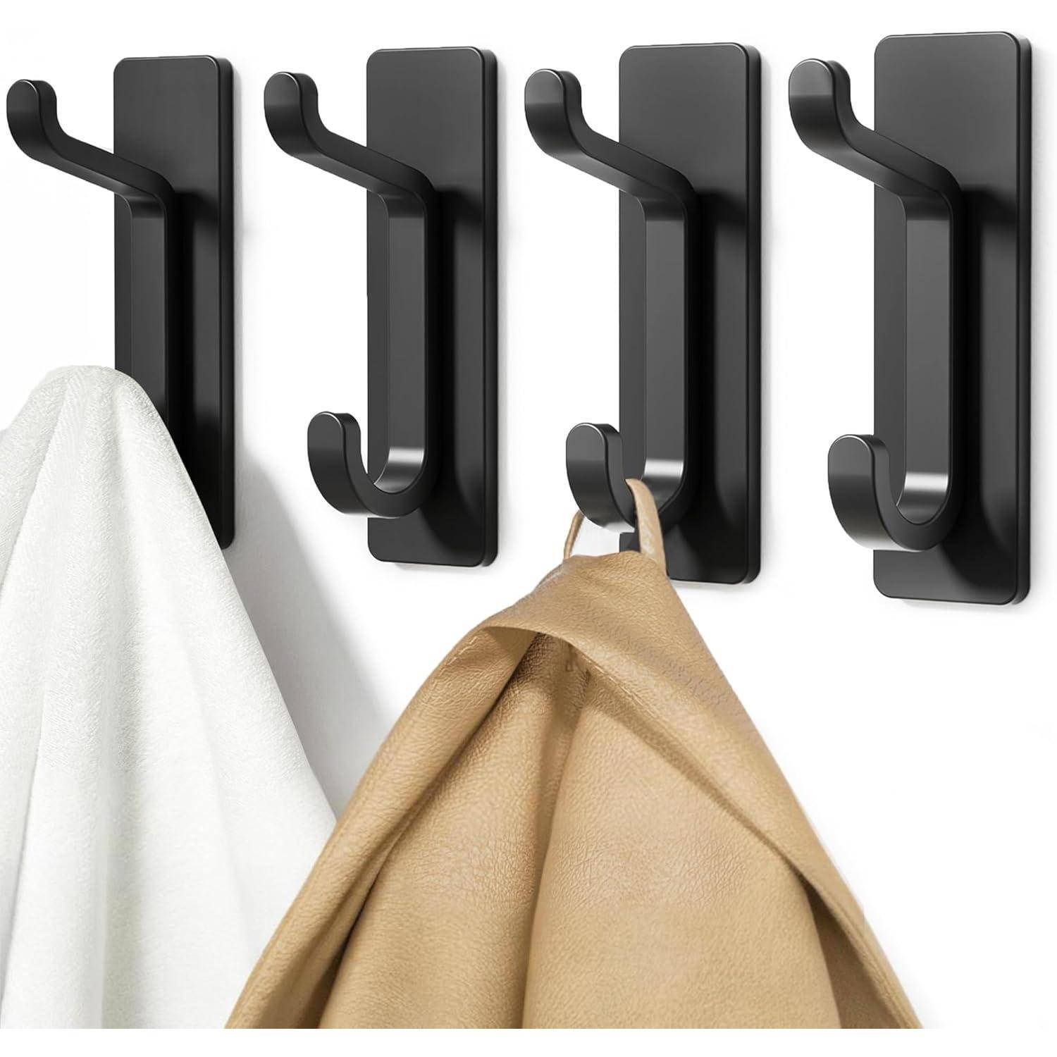 Schwarze Wandhaken mit einem weißen Handtuch und einer braunen Jacke aufgehängt, die Organisations- und Aufbewahrungsmöglichkeiten veranschaulichen.
