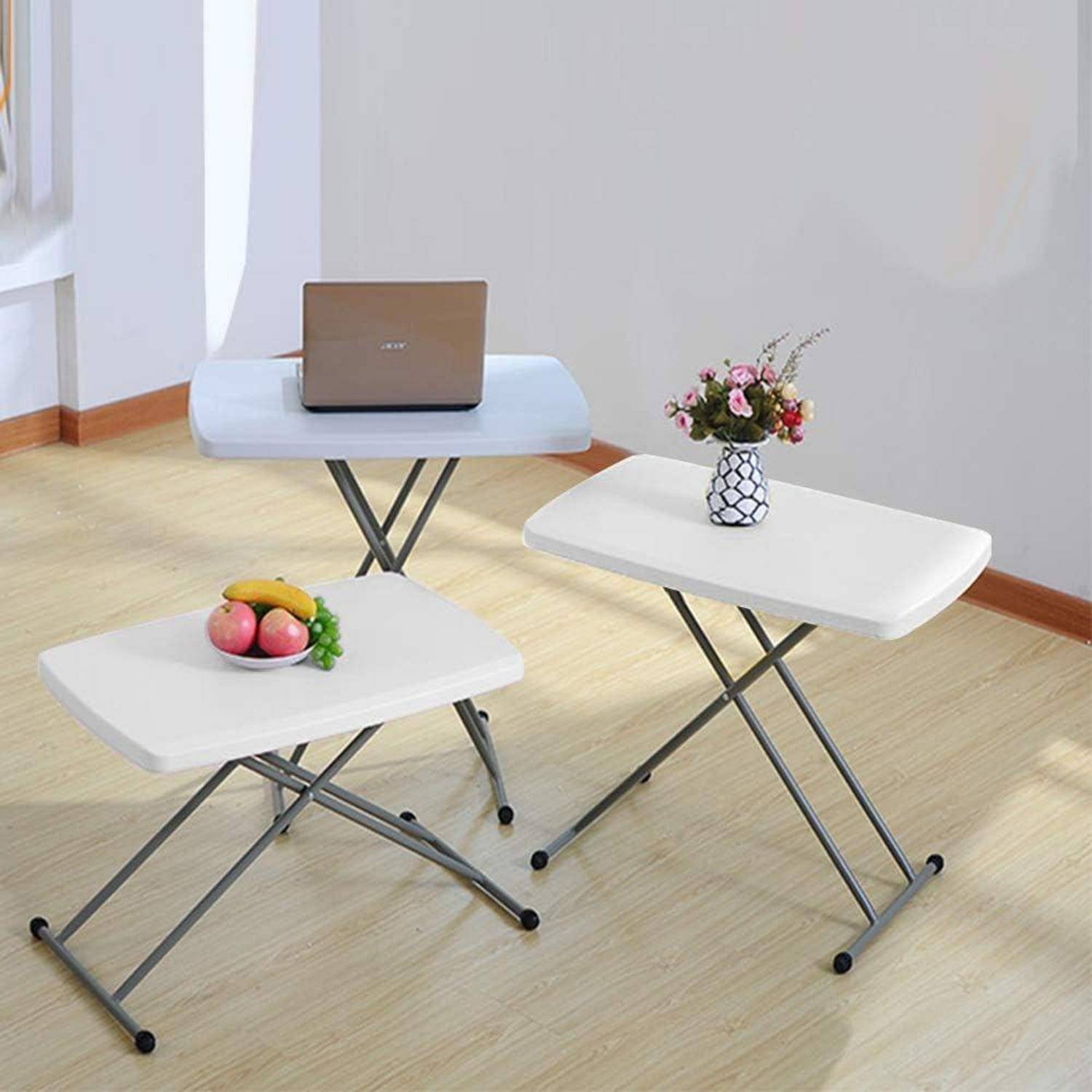 Drei klappbare Tische mit Metallbeinen in einem Raum. Der vordere Tisch trägt Obst, der mittlere Tisch hat einen Laptop, und der hintere Tisch trägt eine Vase mit Blumen.