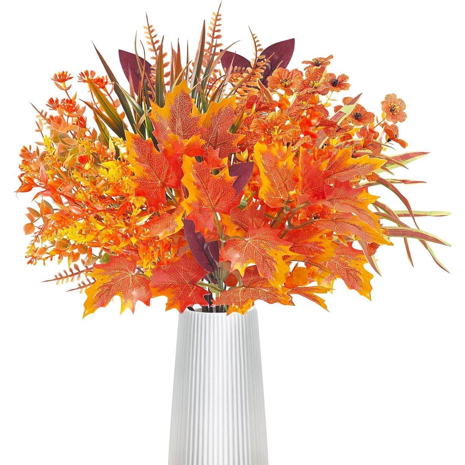 Eine hohe weiße Vase trägt eine lebendige Herbstkomposition mit orangefarbenen Blättern, gelben Blüten und dunklen marronroten Stängeln.