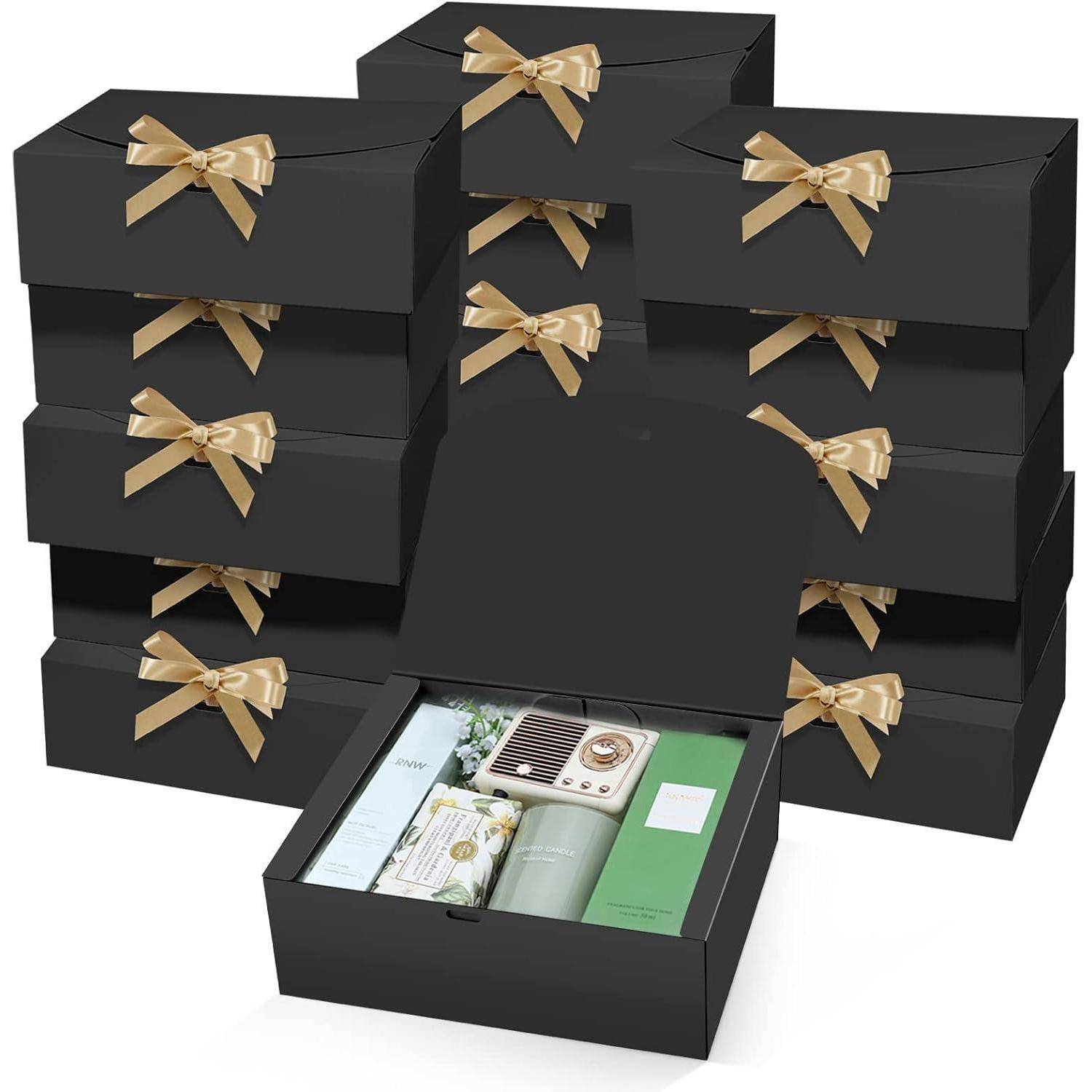 Ein Stapel schwarzer Geschenkboxen mit goldenen Schleifen, eine davon geöffnet und Hautpflegeprodukte enthaltend, darunter eine Flasche, eine Tube und Gläser im Inneren.