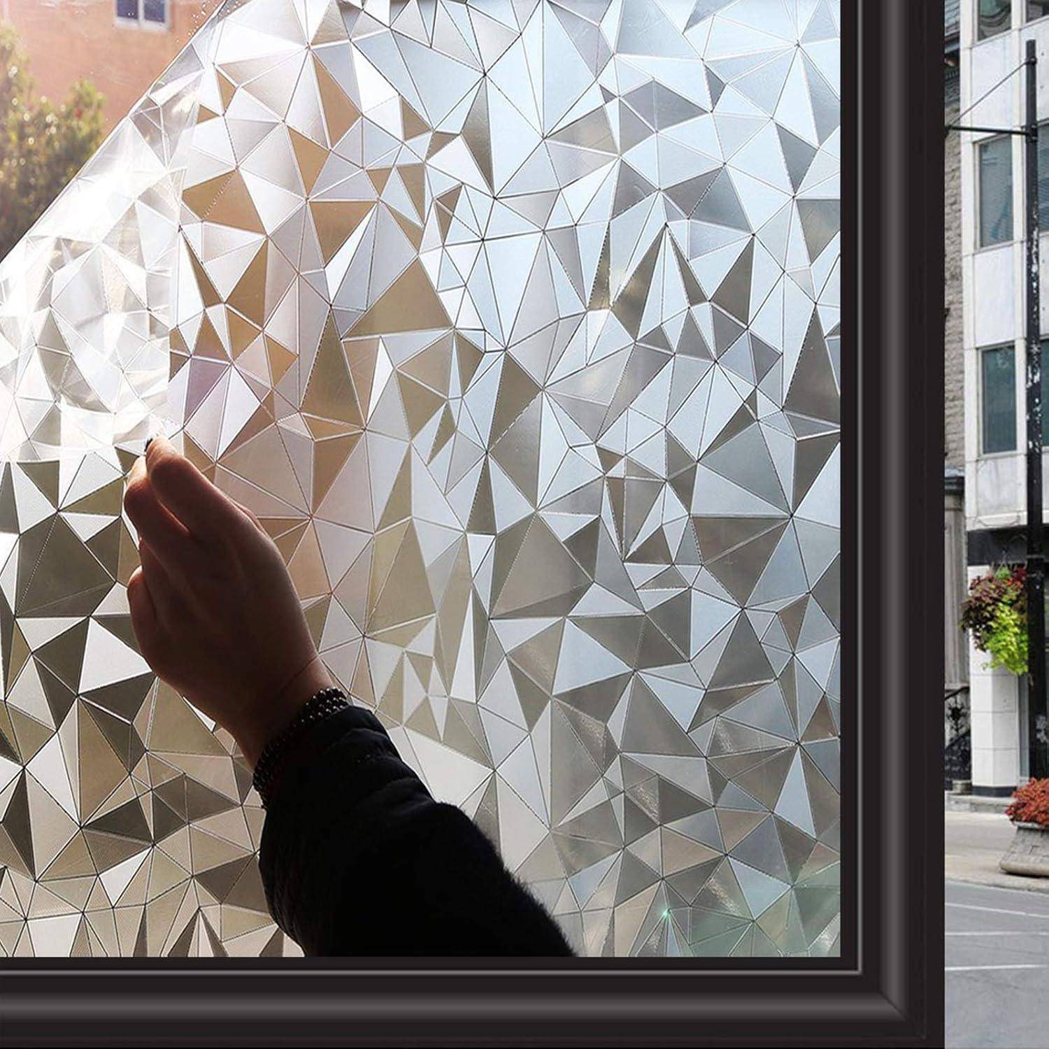 Eine Hand berührt ein Fenster mit einer geometrischen, facettierten Sichtschutzfolie, die Lichtmuster nach innen wirft. Gebäude sind draußen zu sehen.