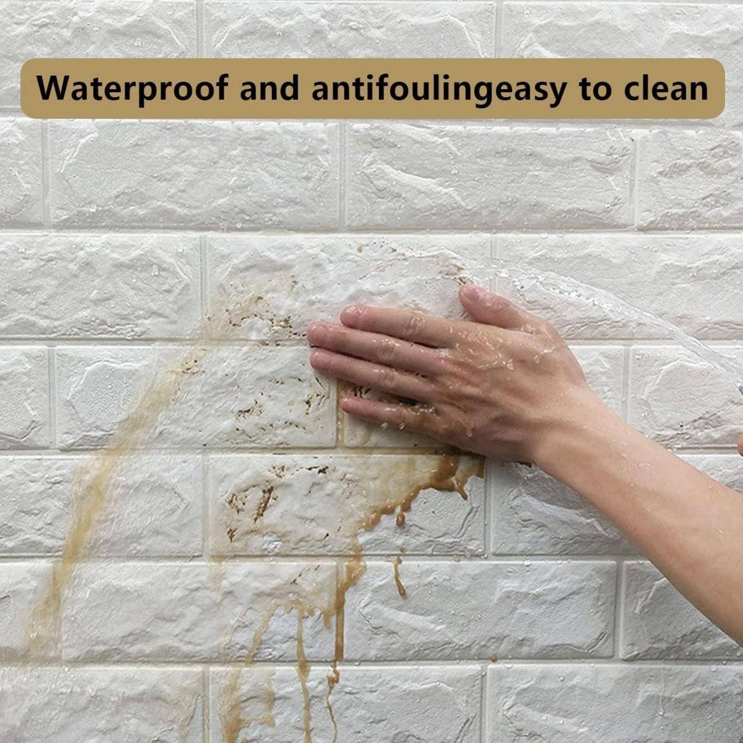 Eine Hand wischt einen braunen Fleck von einer strukturierten weißen Kachelwand. Der Text darüber liest sich: „Wasserdicht und verschmutzungsabweisend - leicht zu reinigen.