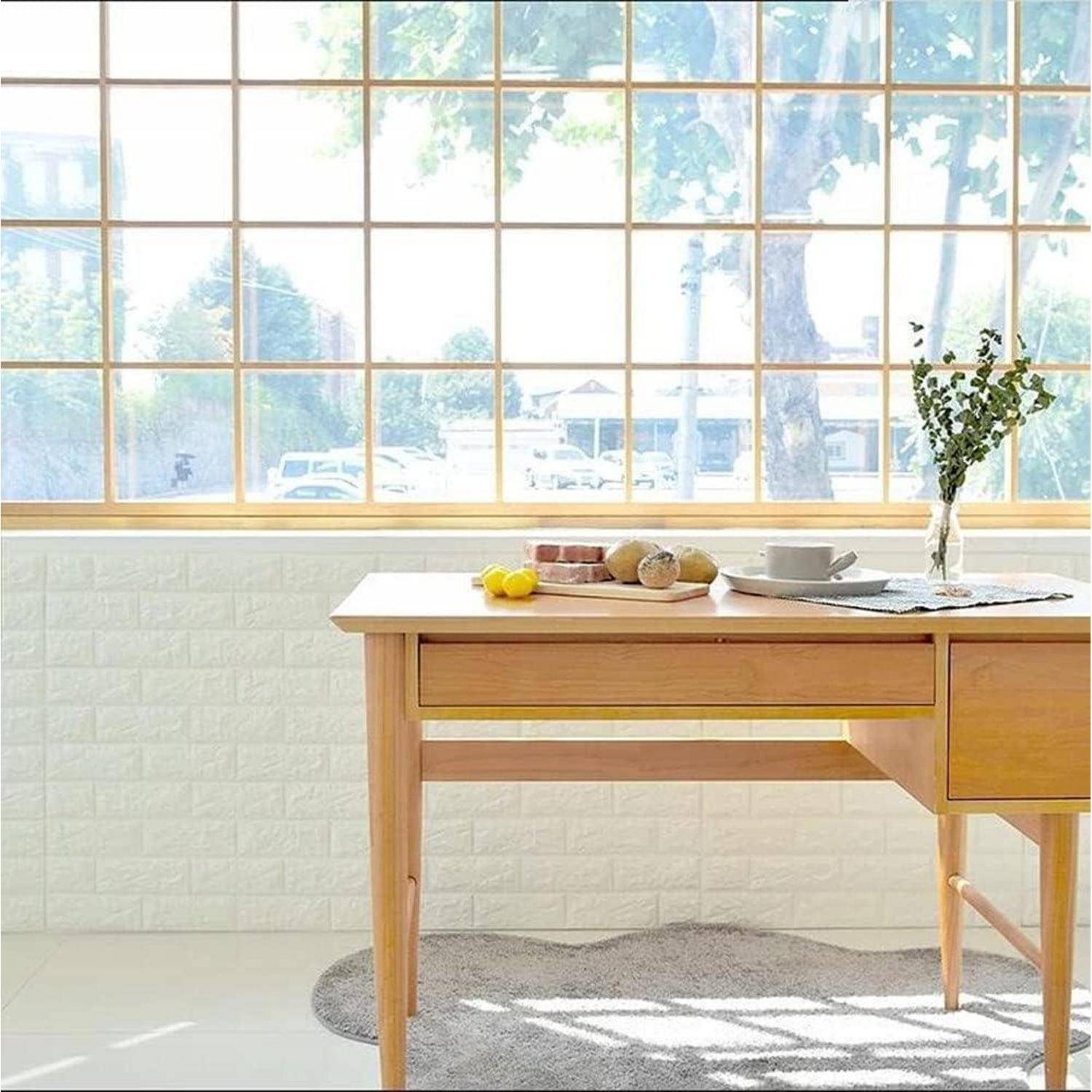 Ein Holztisch an einer großen, vergitterten Fensterwand mit einer Kaffeetasse, einem Teller mit Brot und einer Blumenvase. Helle, luftige Atmosphäre.