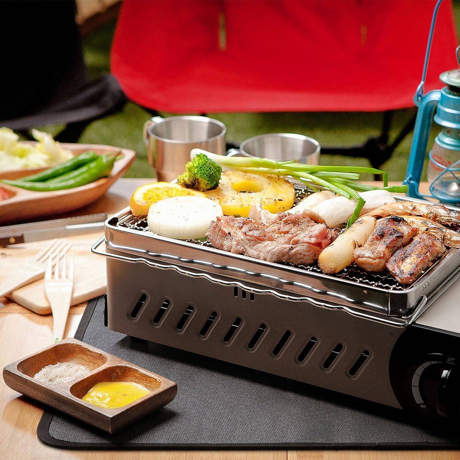 Gegrilltes Fleisch und Gemüse auf einem Tisch-Holzkohlegrill; umfasst Steak, Pilze, Mais und Brokkoli; Ambiente im Freien.