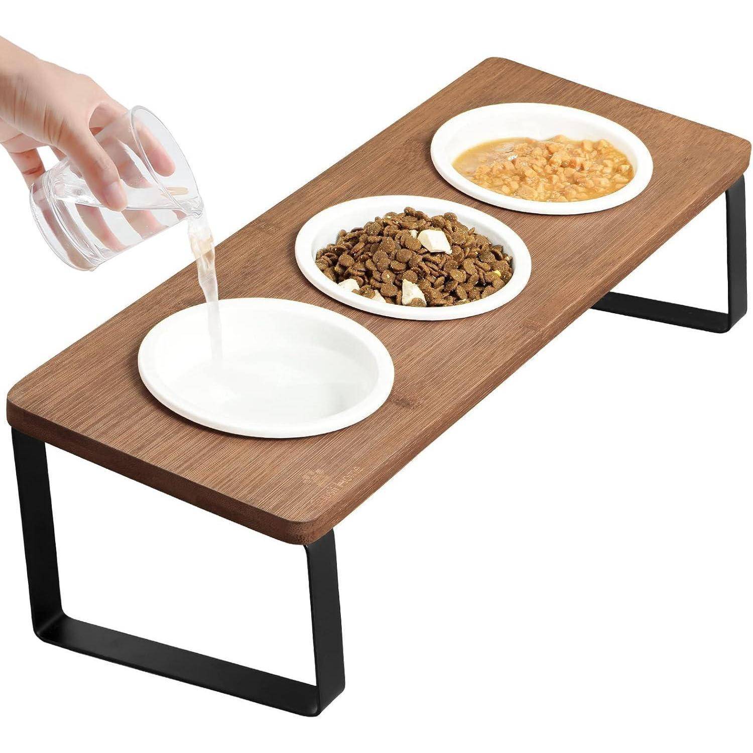 Ein erhöhter Holz-Futterstation für Haustiere mit drei Schalen: eine wird mit Wasser gefüllt, eine andere enthält trockenes Futter und die dritte nasses Futter.