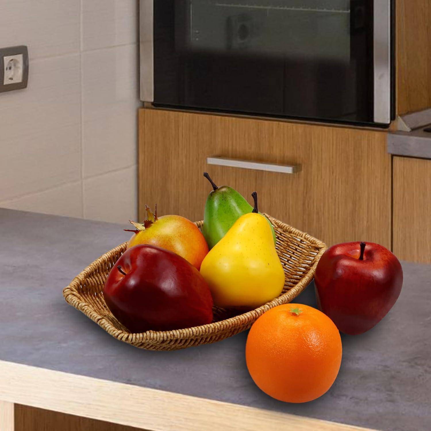 Ein Korb auf der Küchenablage enthält rote Äpfel, gelbe Birnen und eine Orange, während im Hintergrund ein Herd steht.