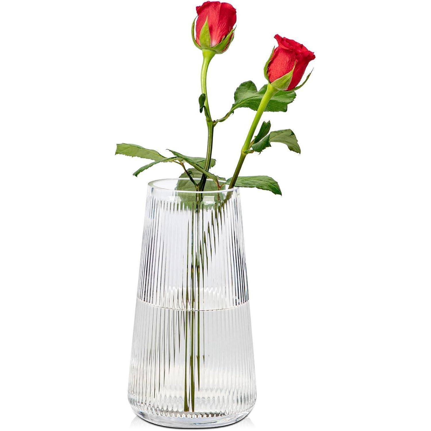 Zwei rote Rosen in einer klaren, gerippten Vase.