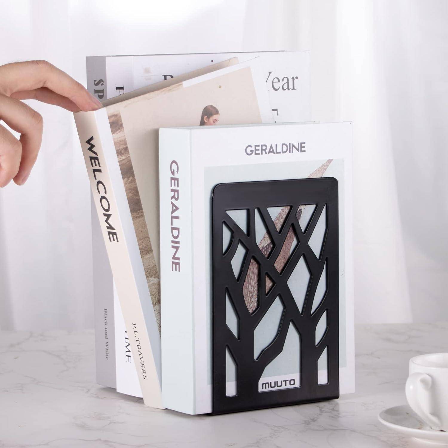 Eine Hand greift danach, ein Buch aus einem stilvollen Buchständer zu nehmen, der ein geometrisches Design und das Wort 'muuto' zeigt. Bücher mit den Titeln 'Welcome' und 'Geraldine' sind zu sehen.
