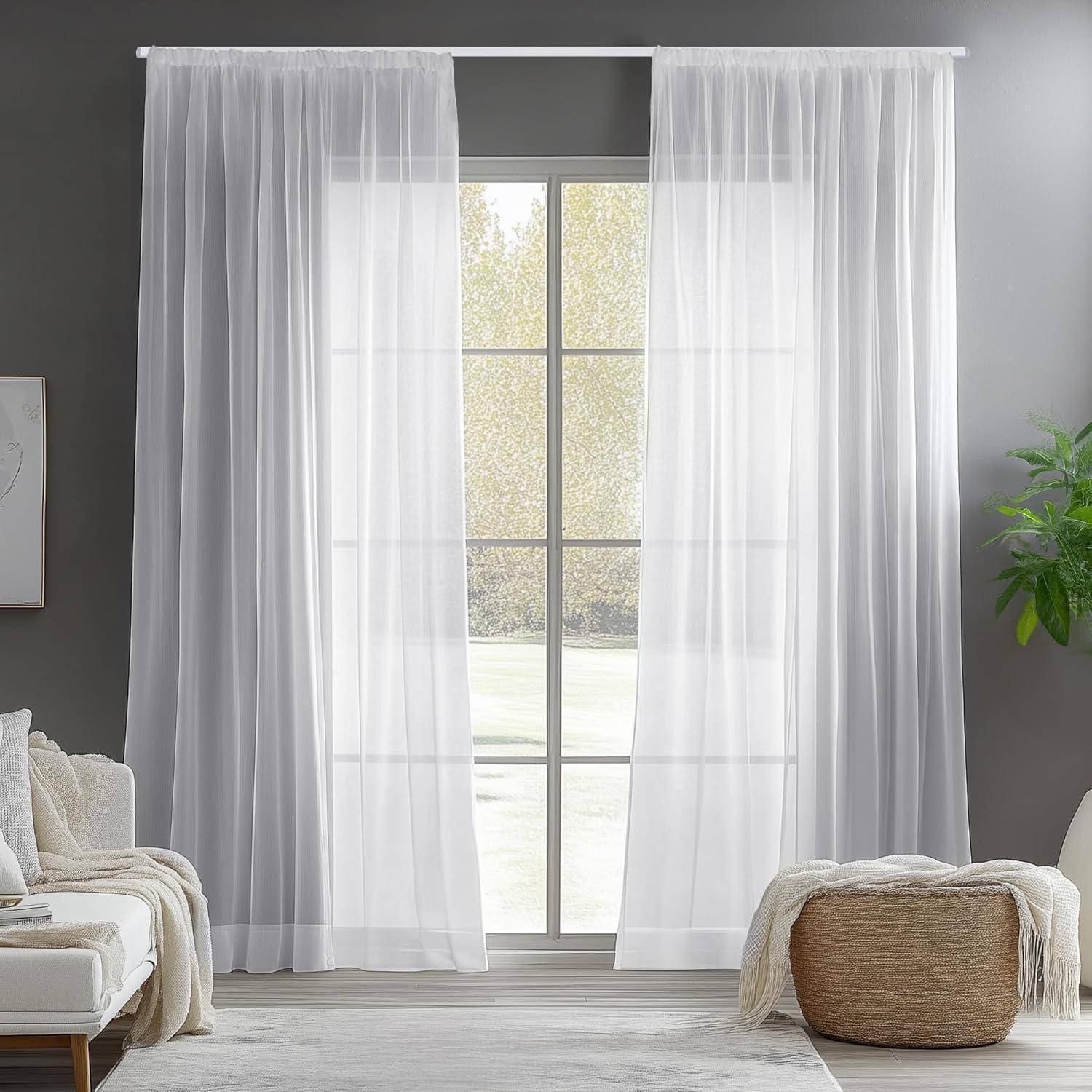 Durchsichtige weiße Gardinen hängen über einem großen Fenster in einem Wohnzimmer und lassen weiches Licht herein. Eine Pflanze und Möbel sind in der Nähe sichtbar.