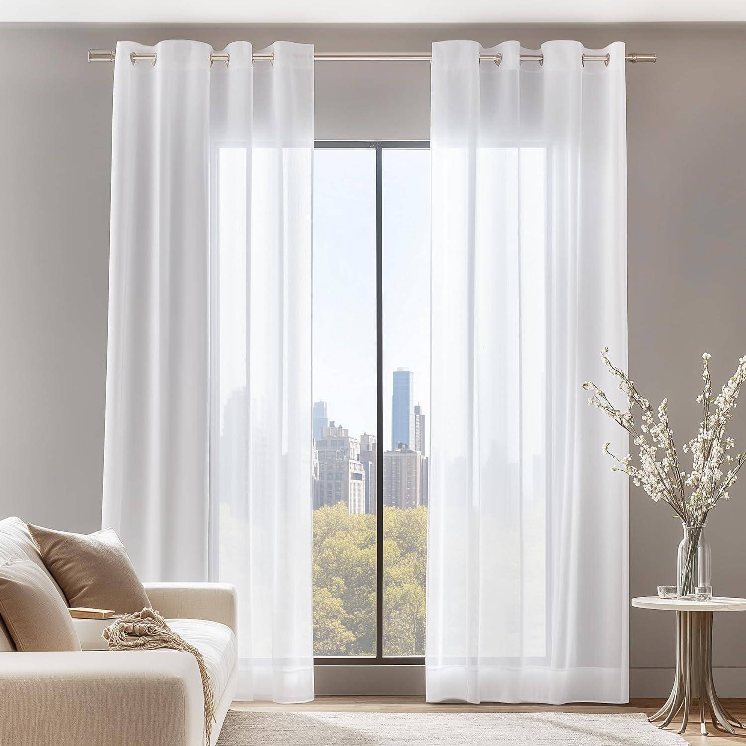 Ein Wohnzimmer mit einem großen Fenster, das eine Stadtlandschaft zeigt. Leichte Vorhänge rahmen die Aussicht. Ein beige Sofa steht im Vordergrund.