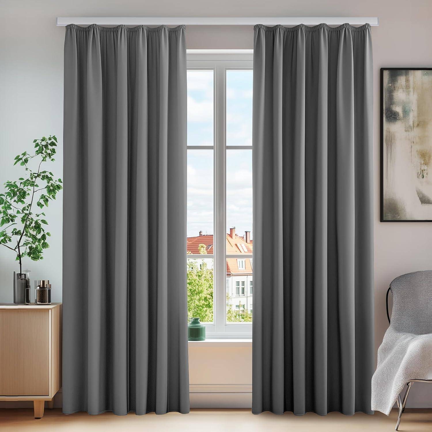 Ein Raum zeigt graue Vorhänge, die ein Fenster umrahmen und dabei einen Blick auf rotdachige Gebäude außerhalb freigeben. Eine Pflanze und ein Schrank befinden sich links.