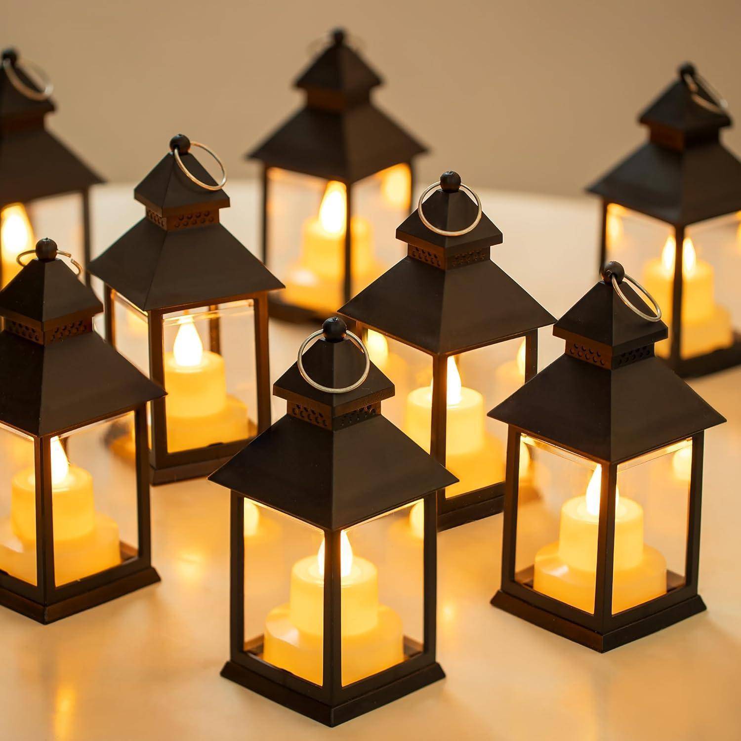 Acht schwarze Metalllaternen mit brennenden Kerzen im Inneren sind in einem symmetrischen Muster auf einer glatten, hellgefärbten Oberfläche angeordnet.