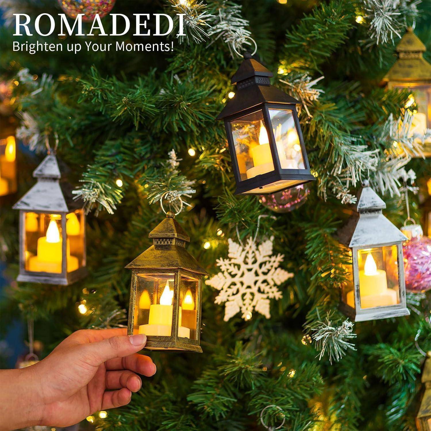 Eine Hand hängt eine Laternenzierde an einen mit Lichtern und Dekorationen geschmückten Weihnachtsbaum. Text in der oberen linken Ecke liest: 'ROMADEDI Erhelle deine Momente!