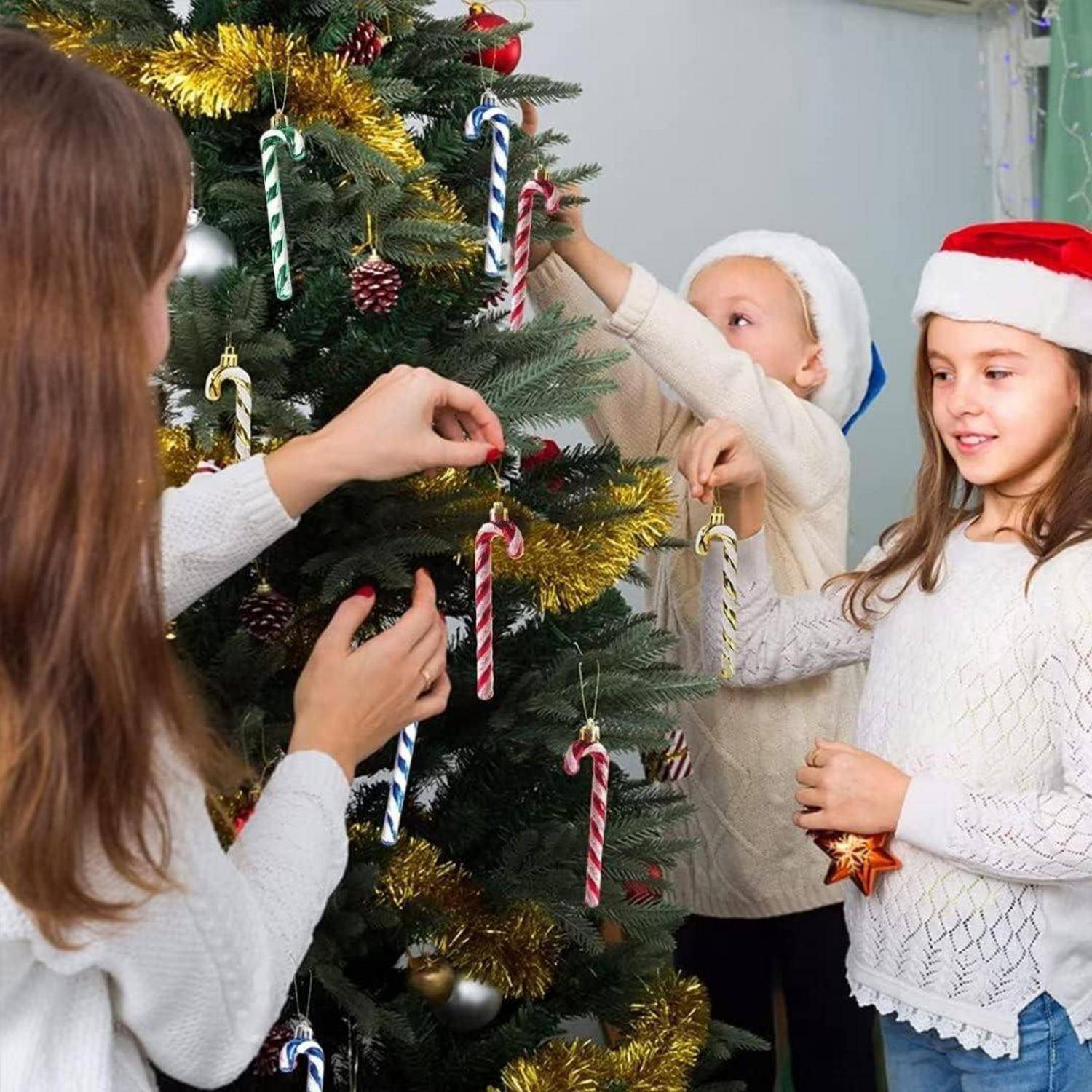 Drei Kinder schmücken einen Weihnachtsbaum mit Zuckerstangen und Weihnachtskugeln und genießen gemeinsam eine festliche Aktivität in der Ferienzeit.