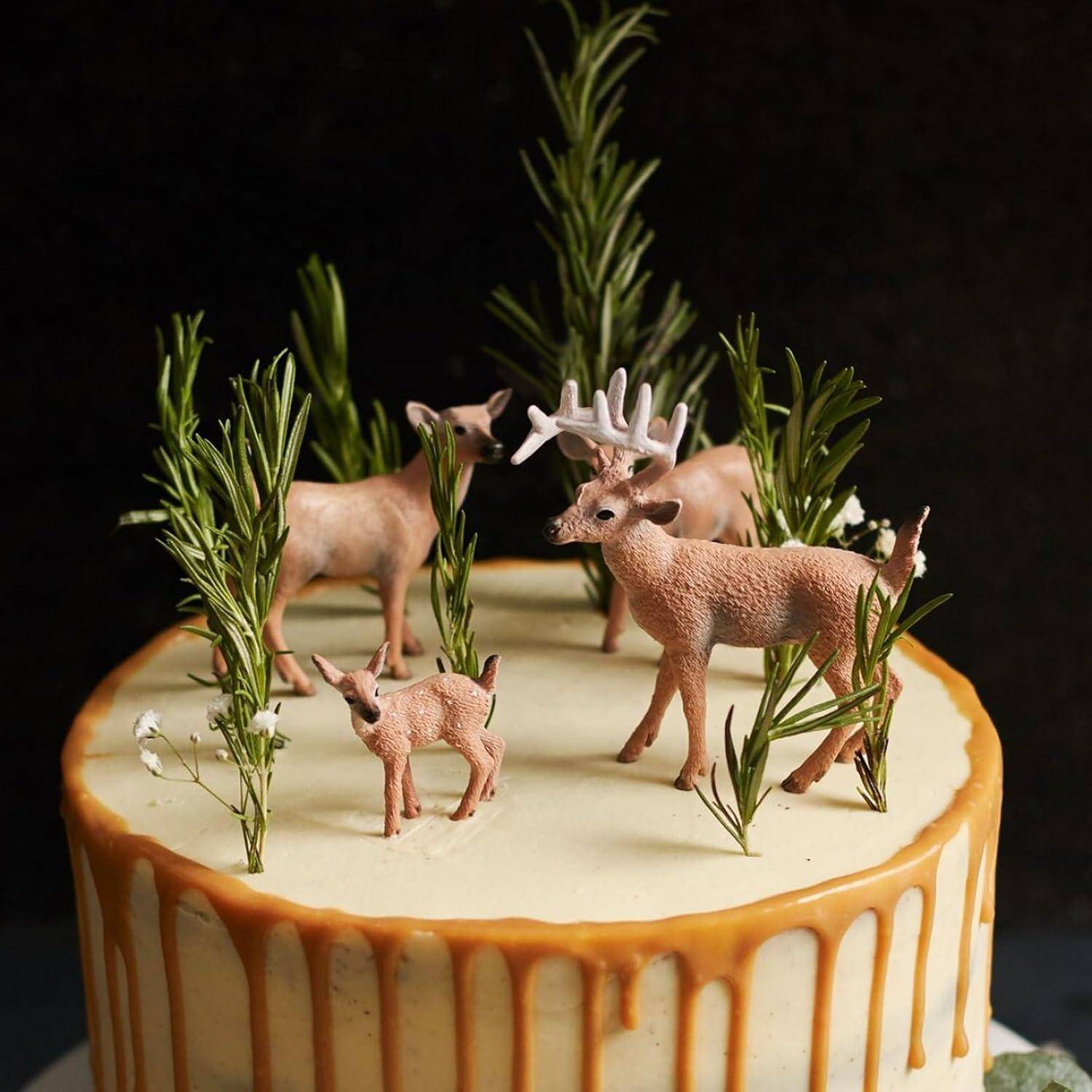 Eine Torte, die mit realistischen Hirschfiguren und Grünzweigen verziert ist, mit einer Karamellglasur, die an den Seiten herabläuft.
