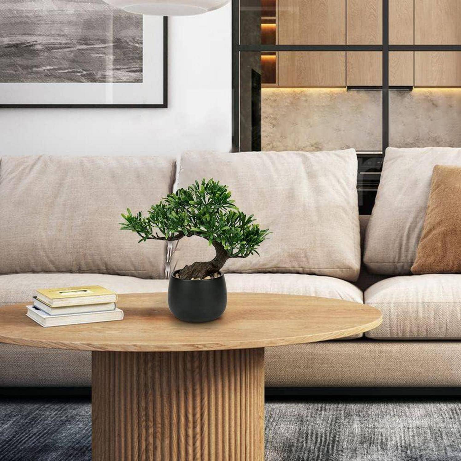 Ein modernes Wohnzimmer mit einem beigen Sofa und einem Holzcouchtisch. Eine kleine Topfpflanze und gestapelte Bücher liegen auf dem Tisch. Ein großes Fenster im Hintergrund.
