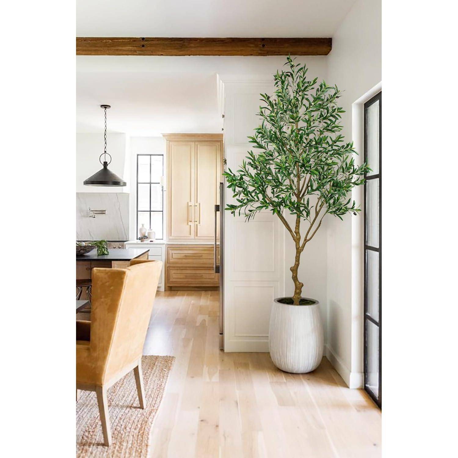 Eine helle Küche mit einem Essbereich, der einen modernen Tisch, Lederstühle in Tanfarbe und eine große Topfpflanze in einem weißen Topf an der Wand umfasst.