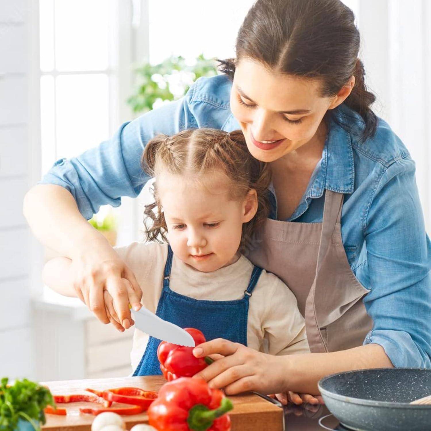 Eine Frau und ein Kind lächeln, während sie rote Paprika in einer hellen Küche schneiden, was eine gemeinsame Kochaktivität andeutet.