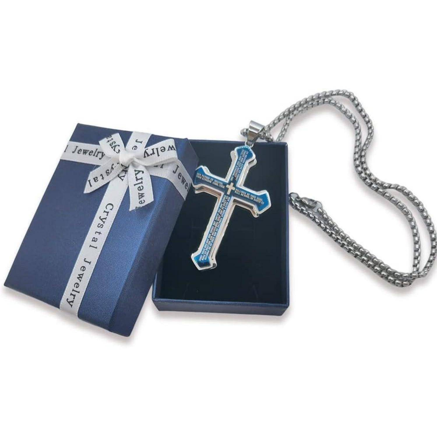 Eine blaue Geschenkbox mit einem weißen Band, die eine silberne Kreuzkette mit einer Gravur enthält, die auf einem blauen Samtuntergrund ruht.
