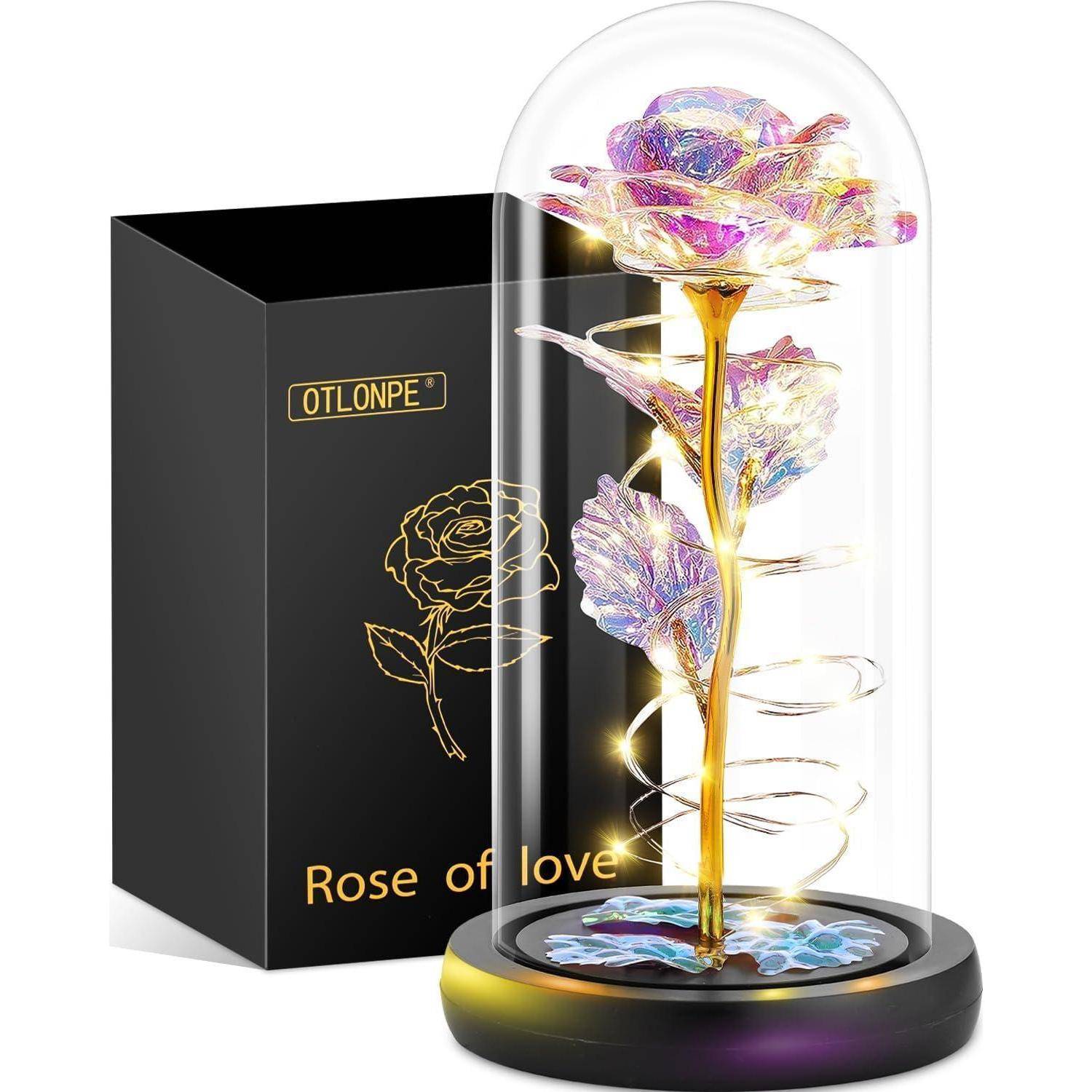 Eine holografische Rose unter einer Glaskuppel mit leuchtenden Lichtern auf einer schwarzen Basis, daneben eine schwarze Schachtel mit der Aufschrift 
