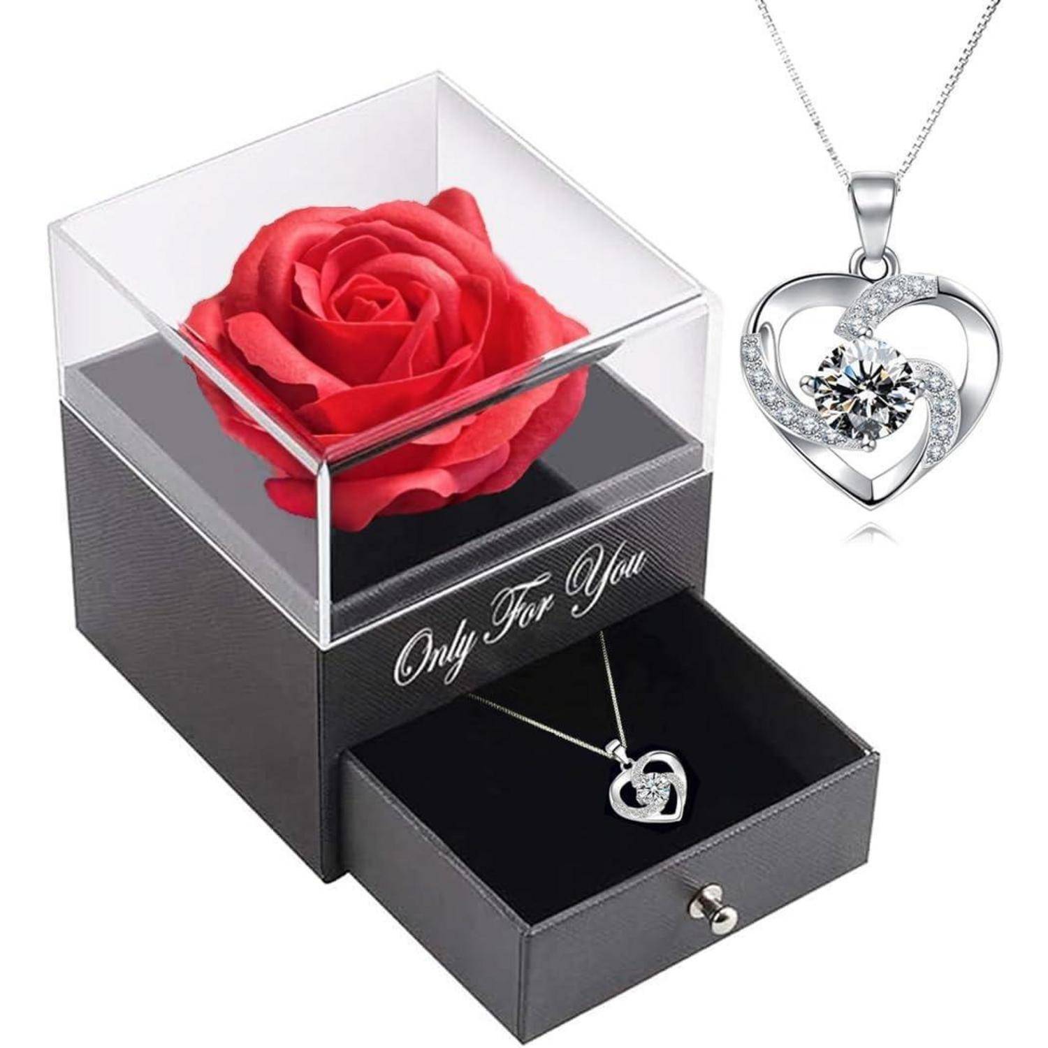 Ein herzförmiger Anhänger mit einem Kristallzentrum wird an einer Halskette präsentiert, aufbewahrt in einer schwarzen Box mit einer roten Rose obenauf und dem Text ‚Nur für Dich'.