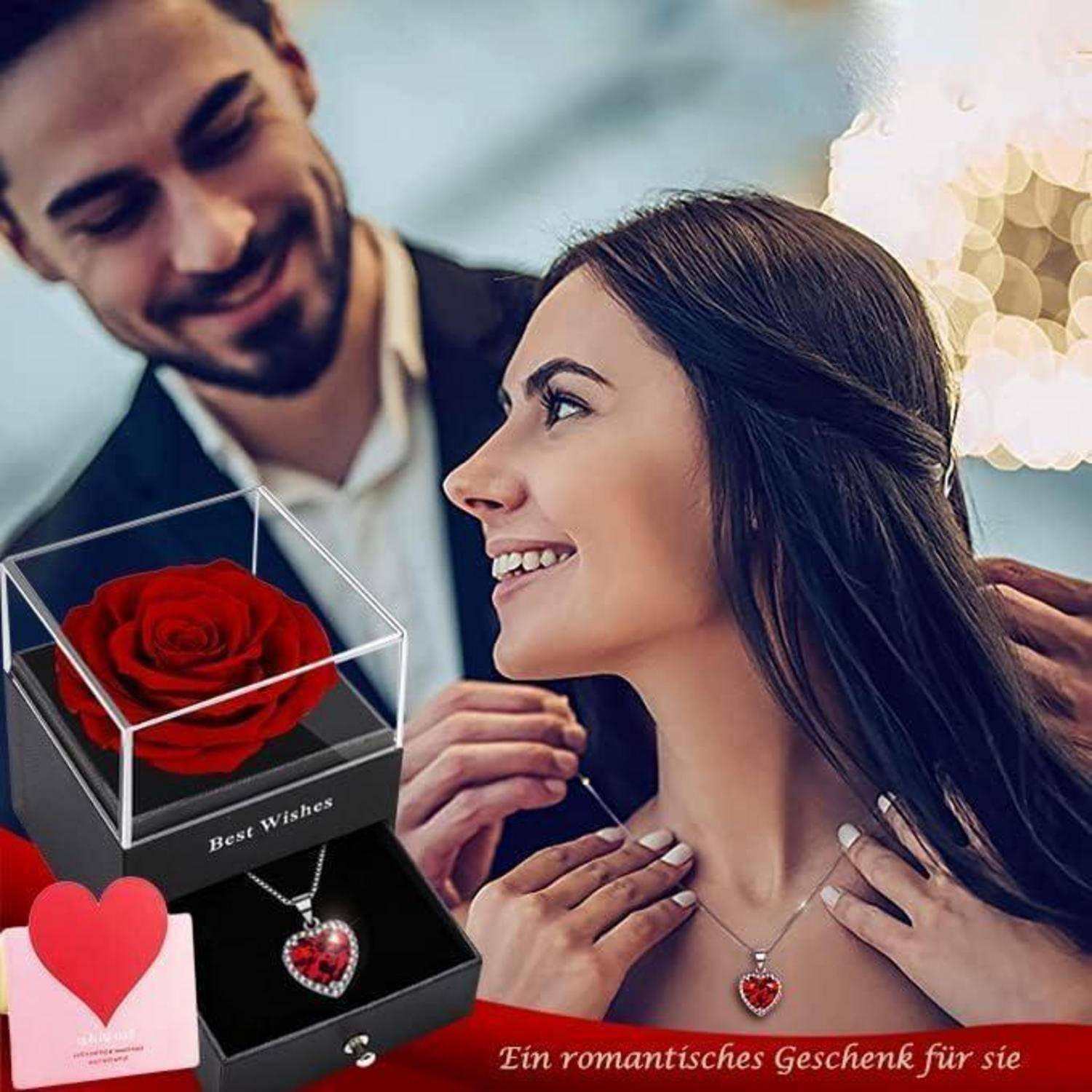 Ein Paar lächelt liebevoll; der Mann legt der Frau eine herzförmige Medaillon-Halskette um. Eine Geschenkbox mit einer roten Rose ist im Vordergrund.
