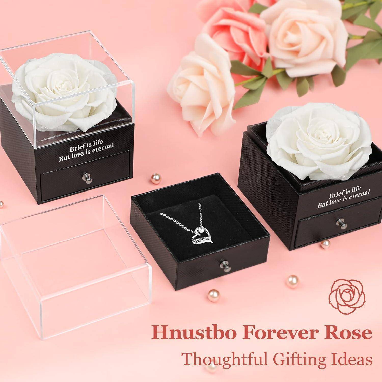 Eine weiße Rose in einer transparenten Box über einer kleinen Schublade enthält einen Herzanhänger. Der Text lautet: „Das Leben ist kurz, aber die Liebe ist ewig. Hnustbo Forever Rose. Durchdachte Geschenkideen.