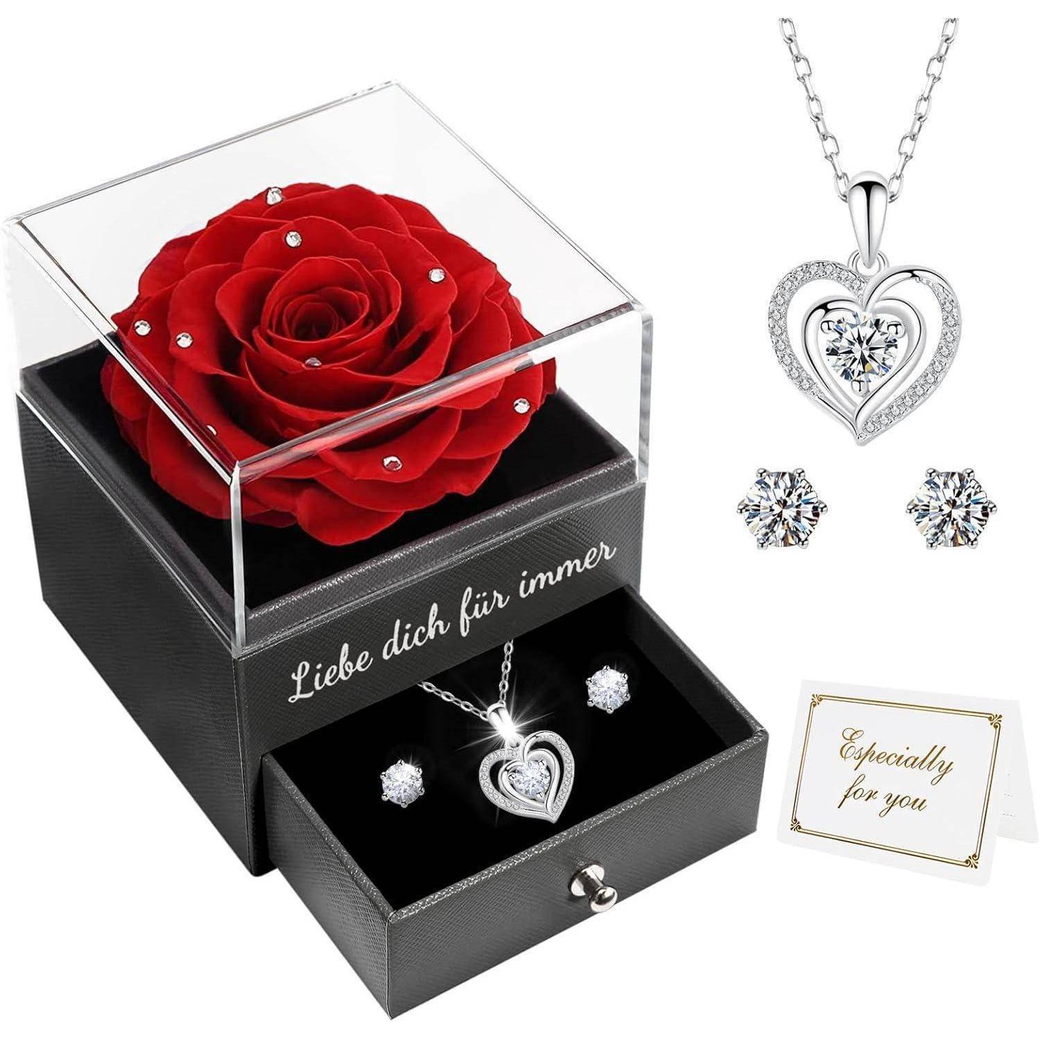 Eine konservierte rote Rose in einer durchsichtigen Box mit der Aufschrift 'Liebe dich für immer'. Darunter ein Schmuckset mit einem Herzanhänger, Ohrringen und einer Karte mit der Aufschrift 'Nur für dich'.