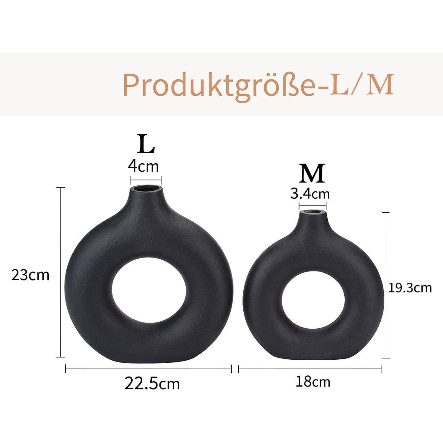 Abbildung zeigt zwei schwarze ringförmige Vasen mit Abmessungen. Die größere Vase (L) ist 23 cm hoch und 22,5 cm breit. Die kleinere Vase (M) ist 19,3 cm hoch und 18 cm breit.