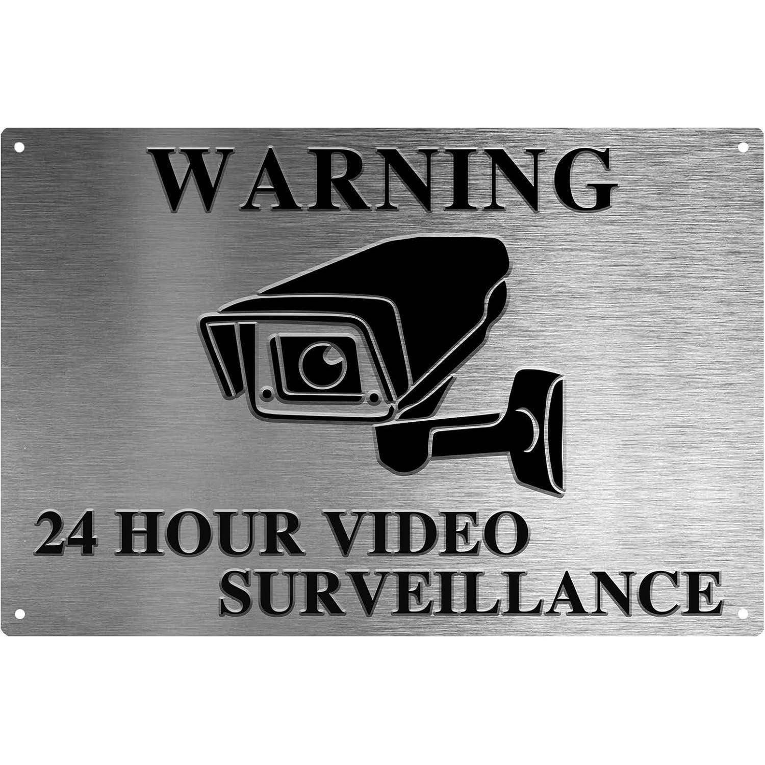 WARNUNG 24-STUNDEN-VIDEOÜBERWACHUNG mit einem Kamera-Symbol auf einem metallischen Hintergrund.