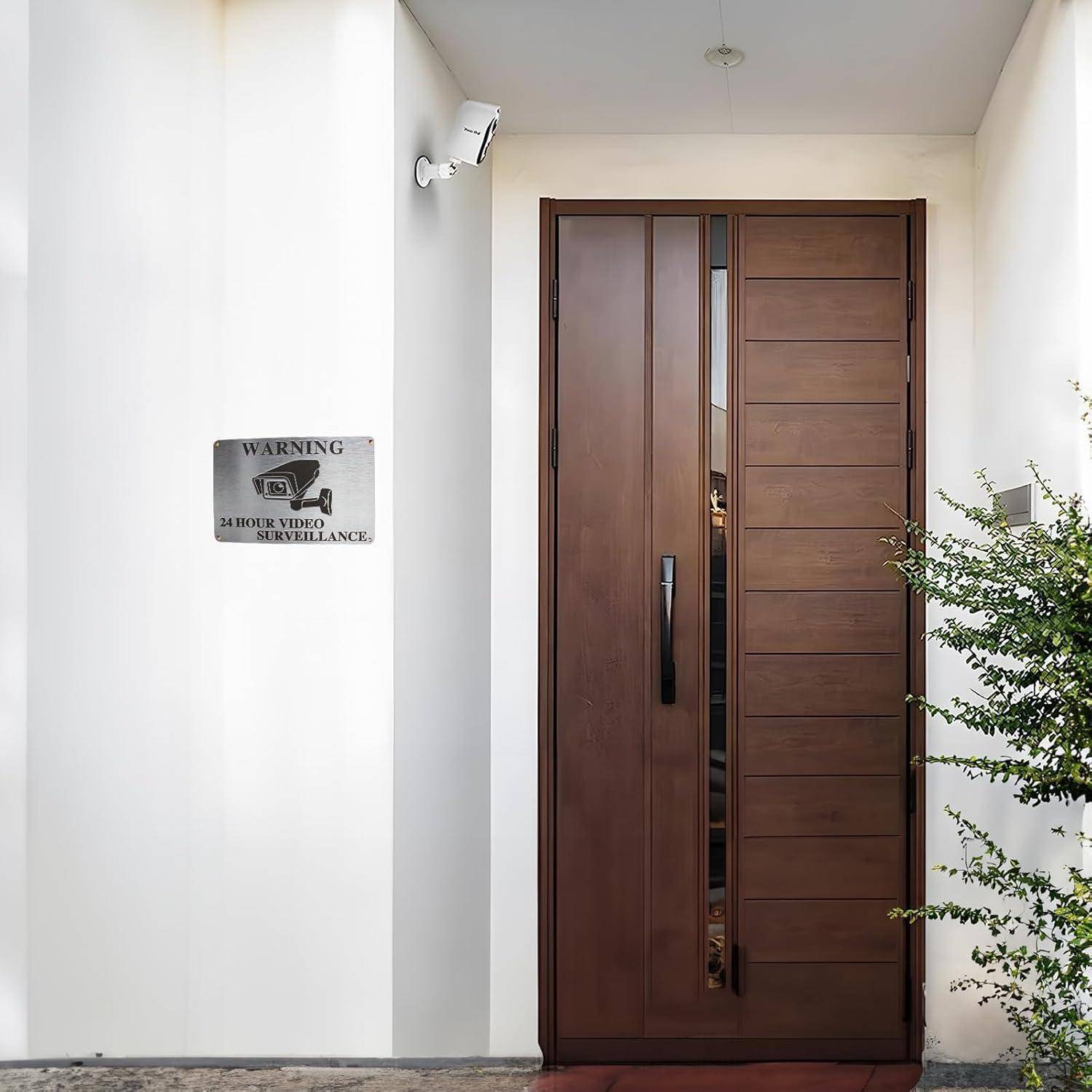 Moderne Holz-Eingangstür mit vertikalen Paneelen, einer Sicherheitskamera darüber und einem Schild mit der Aufschrift 