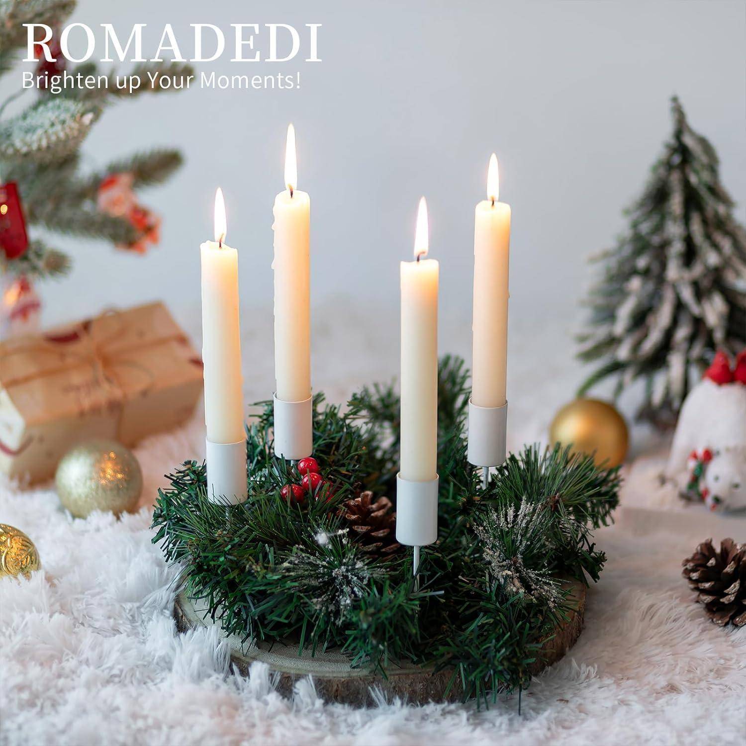 Ein festlicher Kranz mit vier brennenden Kerzen auf einer verschneiten Oberfläche, umgeben von weihnachtlichen Dekorationselementen, mit dem Text "Romadedi Erhelle Deine Momente!"