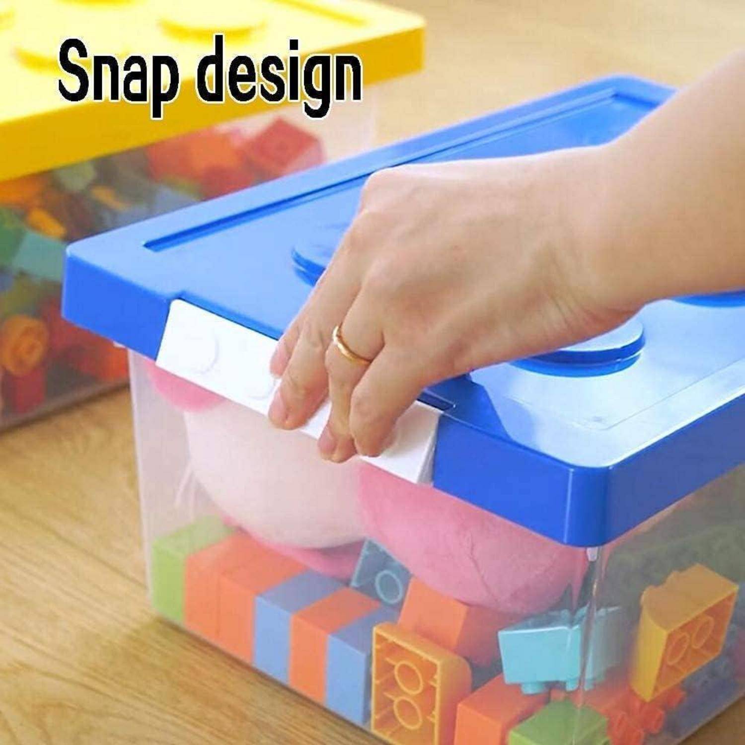 Eine Hand drückt den Clip eines blauen Deckels auf eine transparente Kunststoff-Aufbewahrungsbox, die mit bunten Schaumstoffblöcken gefüllt ist. Text: Snap-Design.