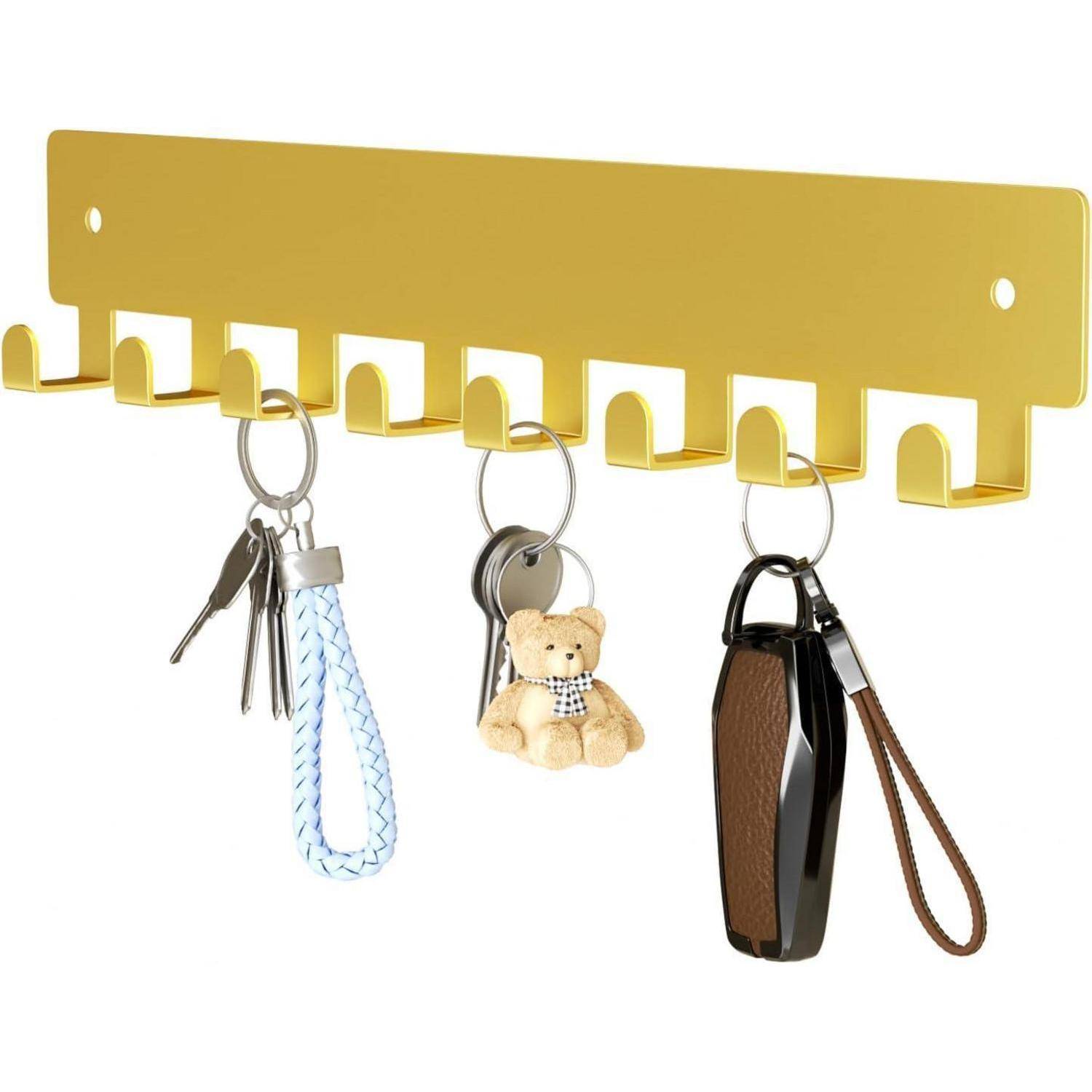 Ein gelber, an der Wand montierter Schlüsselhalter mit Haken, auf dem drei Schlüsselsätze zu sehen sind, ein blauer geflochtener Schlüsselanhänger, ein Teddybär-Schlüsselanhänger und ein schwarzer Schlüsselfob.