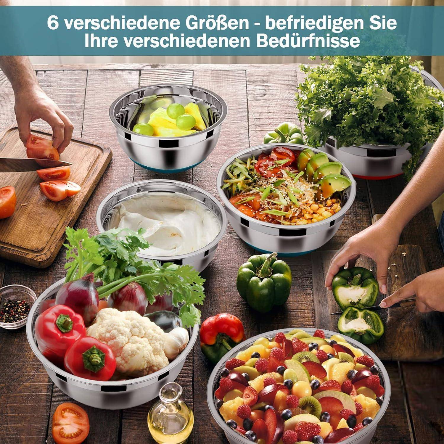 Ein Set von Schüsseln, gefüllt mit frischem Obst und Gemüse auf einem Holztisch. Drei Hände sind zu sehen, die Essen zubereiten und anrichten.