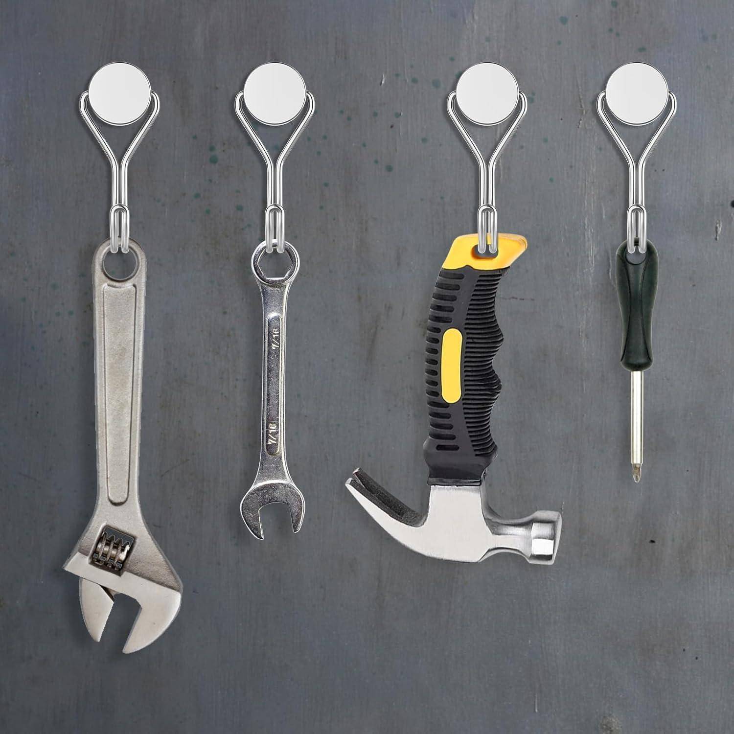Vier Werkzeuge hängen an Haken: ein verstellbarer Schraubenschlüssel, ein Kombischlüssel, ein Hammer mit gelb-schwarzem Griff und ein Schraubendreher.